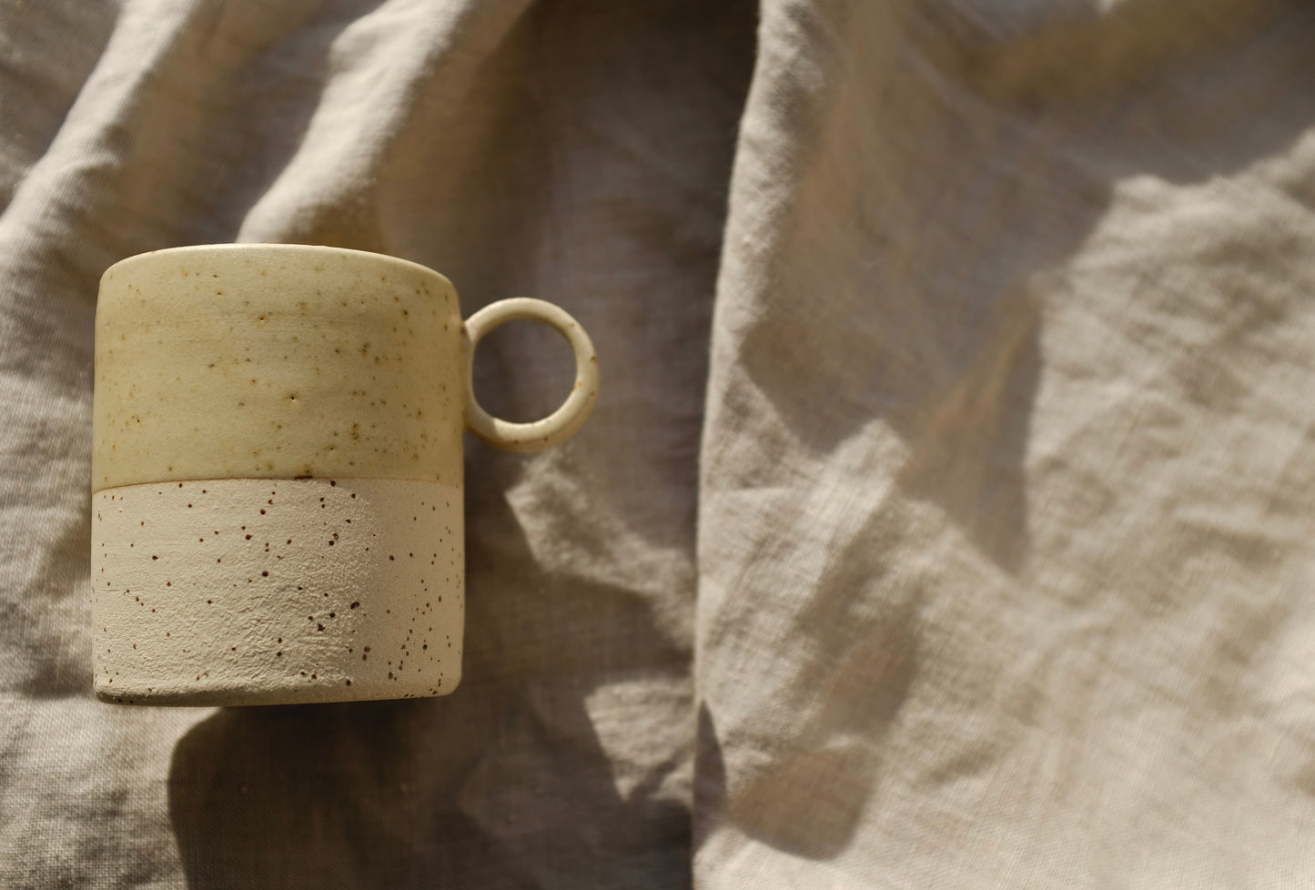 Tasse Aurore, pour le thé ou le café. Bi-matière : couleur crème et grès belge moucheté. Entretien : lave vaisselle. Dimensions : ∅.7,3 x h.8,5 cm - 200 ml