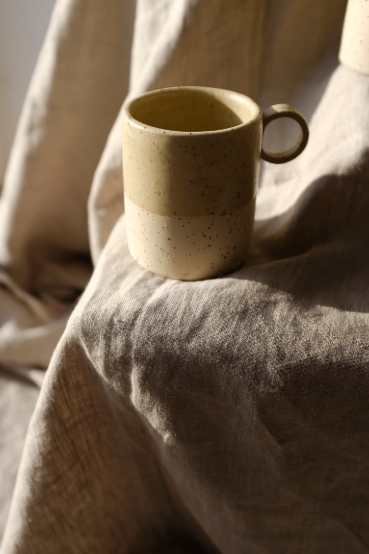 Tasse Aurore, pour le thé ou le café. Bi-matière : couleur crème et grès belge moucheté. Entretien : lave vaisselle. Dimensions : ∅.7,3 x h.8,5 cm - 200 ml